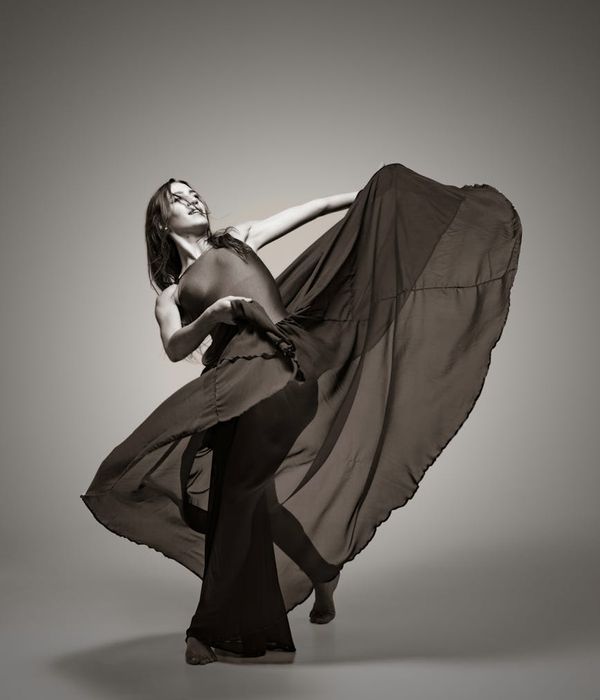 Woman performing a graceful cardio movement in a calm studio environment.